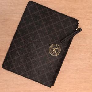  - Clutch svart/brun från Malene Birger i klassiskt mönster. Oanvänd - Nyskick!!!   Storlek: B 25 x H 17 cm
