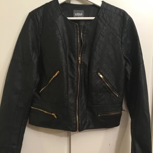  - Skinnjacka i svart med gulddetaljer Nyskick.  Möts i STHLM , huddinge. 