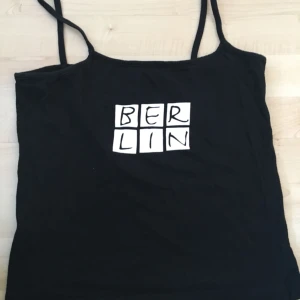  - Svart crop top med tryck på framsidan. Smala axelremmar. 