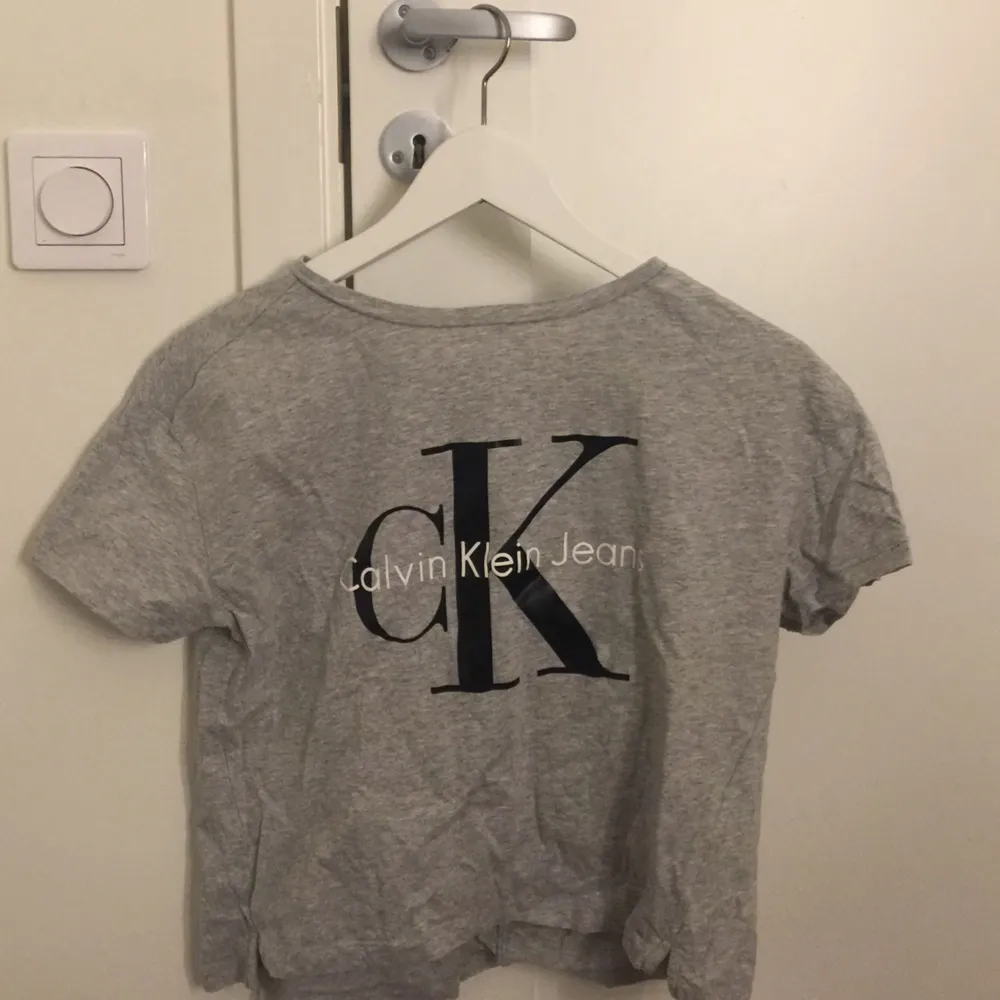 Grå Calvin Klein tröja i den ”croppade” modellen. Använd ett par gånger men har ingen defekt! . T-shirts.