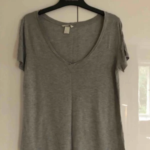  - Ljusgrå v-ringad T-shirt från Hm. (Bilden blev lite mörk). Fint och klassiskt basplagg i bra skick. Strl S men sitter mer som en M