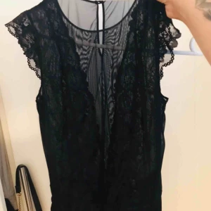  - En spetsbody med genomskinlig urringning och genomskinlig i ryggen. Strl L men passar M.  Köpare står för frakt eller möts upp.