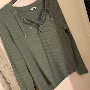 En grön tröja som är med snörning vid bröstet, super fin och lite smått ribbat tyg på den, använt 2 gånger. 