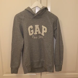 Hoodie från GAP strl XXS - Grå hoodie från GAP i storlek XXS, men skulle mer säga att den är som XS 🤍🤍 Säljer då den inte kommer till användning. Tröjan är i mycket fint skick och är endast använd enstaka gång 😊 Samfraktar gärna med andra plagg och betalning sker via Swish <33