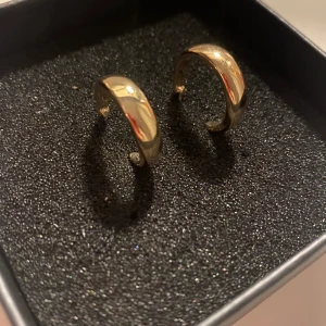 Örhängen - Guldiga örhängesringar, OBS telefonen speglas i smycket