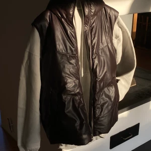 Vadderad väst med skinneffekt | ZARA - OANVÄND ‼️ Väst med hög krage i brun/svart skinneffekt - är samt lite oversized om man är lite kortare 🤎 (prislapp kvar) 