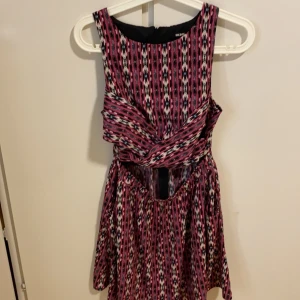 Klänning  - En mönstring klänning med fickor och fin öppning vid magen bara framifrån. Oanvänd