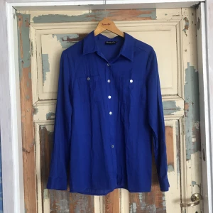  - Klarblå skjorta med pärlmoknappar! Ursprungligen från kappahl men det måste varit väldigt länge sedan. Känns vintage. Swish eller kontant. Kan antingen mötas upp i stockholm eller rosersberg/märsta, eller frakta. Köparen står för frakten. 