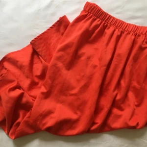  - Röd vid kjol som sträcker sig till smalbenen.