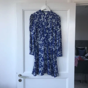  - Underbar klänning från H&M. Lätt utsvängd kjol. Sval och skön. Beklädda knappar längs hela framsidan.  Frakt 40kr