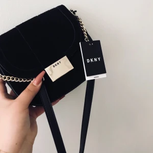  - Säljer en helt ny DKNY väska Väskan har gulddetaljer och är i suede-material Axelremsväska  Nypris: 2299:- Prislappen hänger kvar Dustbag medföljer Kan fraktas mot betalning
