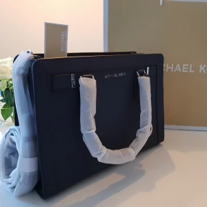  - Michael Kors väska Ny, givetvis original, köpt på Michael Kors i USA.   Modell: Dillon Navy Mått: Bredd : 32 cm Djup :10 cm Höjd :24 cm  Axelband/rem medföljer. Gratis leverans i Söderort. Hör av dig för fler bilder.  