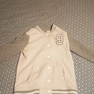 En vår tröja. - Den har två fickor och knappar och en nia på.