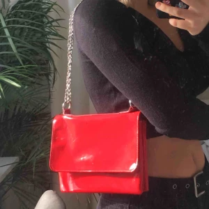  - Röd lackväska från monki. Kedjan kan förlängas eller kortas ner. Köparen står för frakt🦋