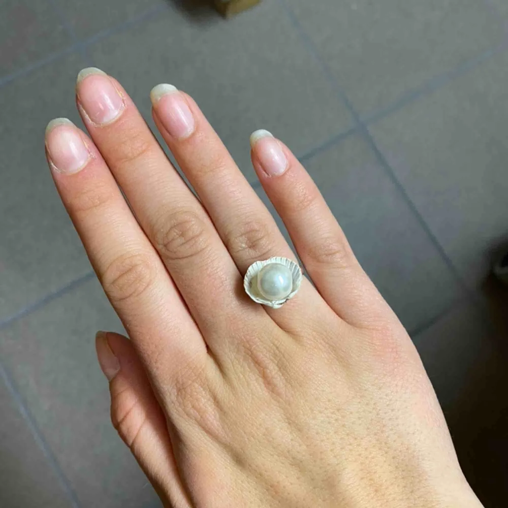 Handjord silvrig ring med äkta snäcka med en vit pärla i. Justerbar i storleken . Accessoarer.