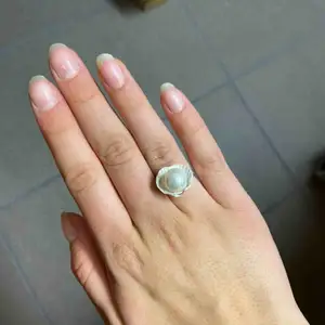 Handjord silvrig ring med äkta snäcka med en vit pärla i. Justerbar i storleken 