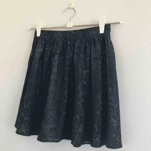  - Supergullig kjol från Ginatricot i strl 34, passar även 36. Grå svart ormmönster med guldig dragkedja i ryggen. Väldigt fint skick, som ny! Skön och luftig. Eventuell frakt tillkommer 💗⚡️