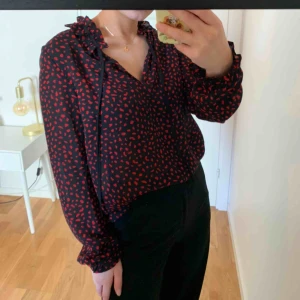  - Svart blus med röda prickar, går att jämföra med leopardmönster ursprungligen från Gina Tricot. Liten slitning vid urringningen, inget man ser när det sitter på, därav priset. 