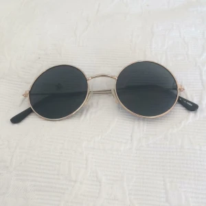  - Runda solglasögon i svart glas och guld-rosé ramar
