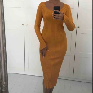  - Gul/orange klänning som formar sig efter kroppen med sjuktfina armar