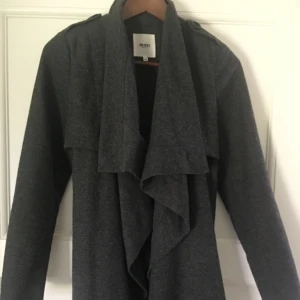  - Mörkgrå kappa från Object som kan knutas både i fram och i bak. Bandet kan även tas bort helt. Ordinarie pris 599kr.