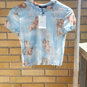 Topp - Jättefin genomskinlig topp med änglar på från bershka, helt oanvänd💖 storlek M men passar nog både mindre och större storlekar då den är väldigt stretchig.