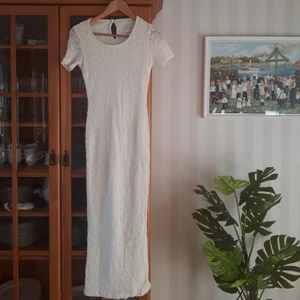 Vit lång klänning - Vit långklänning. På mig som är ca 170cm går den ner till knölen på ankeln. Från armhålan ner längst sömmen är den ca 115cm