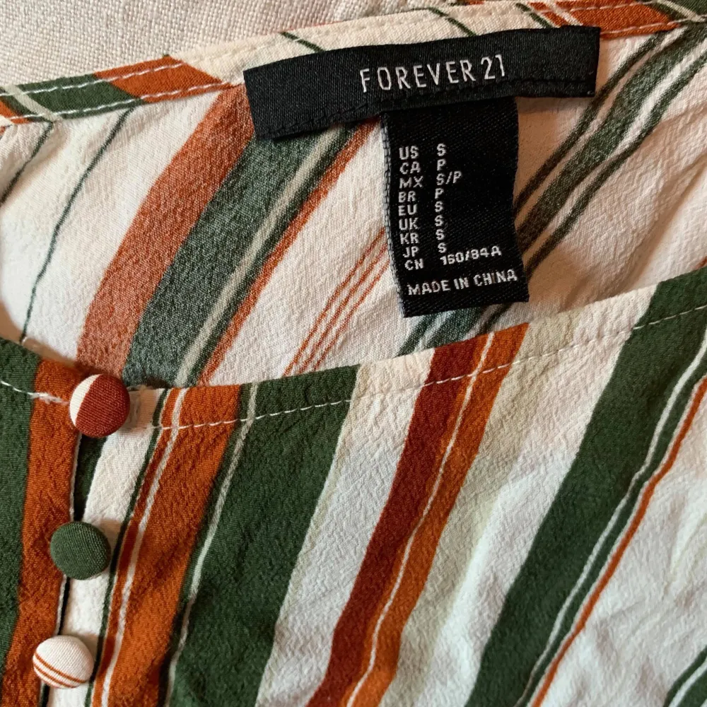 Randigt cropped linne från Forever 21 med knappar på framsidan. Perfekt för sommaren! . Toppar.