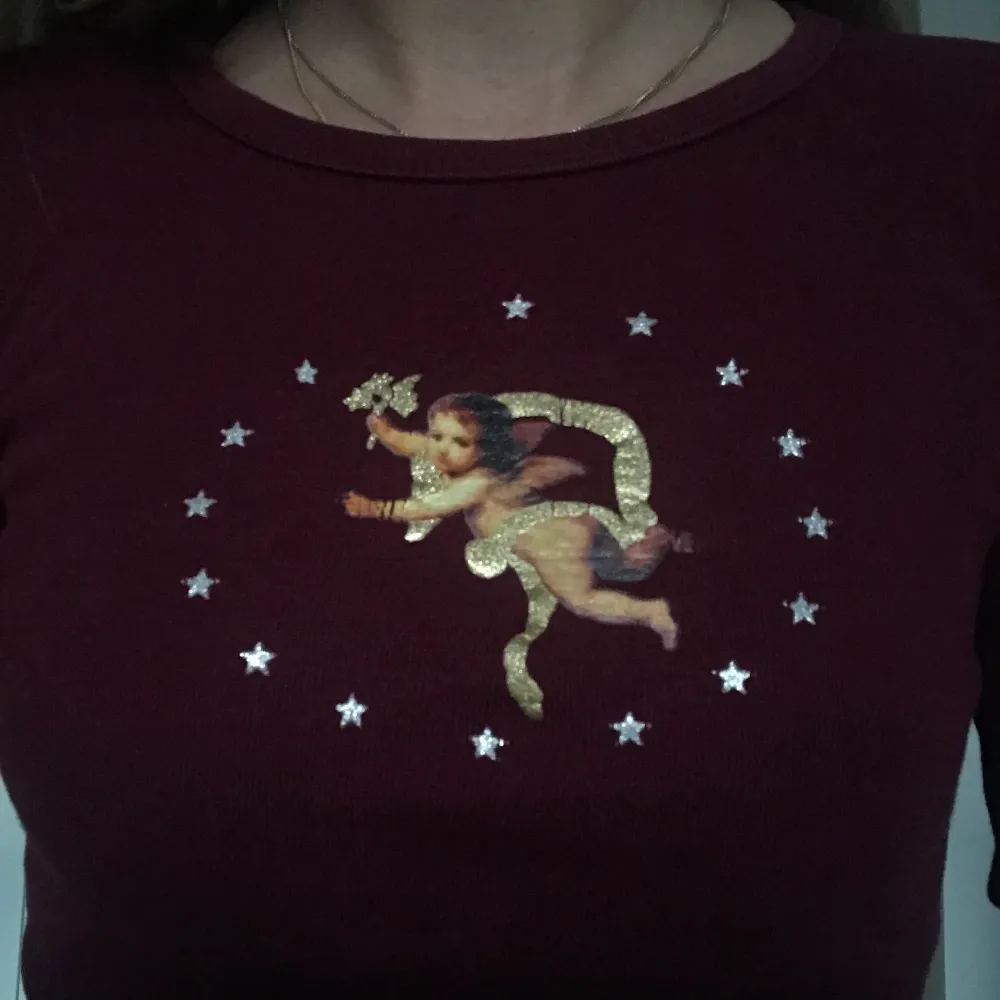 Trekvartslång croppad T-shirt i vinröd med tryck av stjärnor runt ängel. . T-shirts.