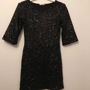  - svart paljett klänning med svart töjbar rygg i tyget storlek XS . Märke ida Sjöstedt 