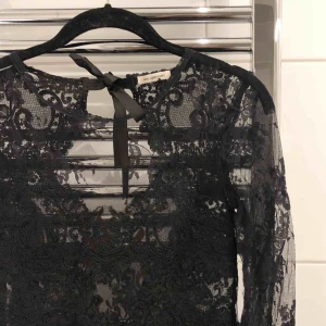  - Klänning från Ida Sjöstedt. Figurnära klänning i exklusiv spets. Trekvartslånga ärmar samt djup v-ringning baktill. Rundad hals och meshtyg blandat med täckande spets framtill. Stängs med dold dragkedja bak.  Använd en gång. Som ny. Nypris 2500:- 