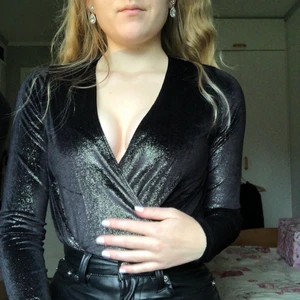 Body xs  - Glittrig svart body i storlek xs. Helt ny med lapparna kvar, från Nelly 💞 Sitter superfint på kroppen, string så syns inte under kjol/byxor. 