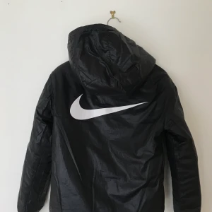 Nike dunjacka - Superfin svart dunjacka från Nike, köpt på stadium förra året för 1200kr. Säljer nu för 400kr + frakt (66kr). Passar mig som är 170cm lång. Jackan går att använda på två håll, man kan alltså vända den ut och in och få en annan design :)
