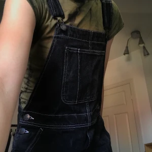 Hängselbyxor - Assnygga svarta hängselbyxor med vita sömmar från monki. Färgen är lite ojämn och urtvättade men annars är dom i bra skick. Dom går ner till fötterna på mig som är ca 176cm. Jag fraktar dom eller möts på Södermalm. Priset kan diskuteras.