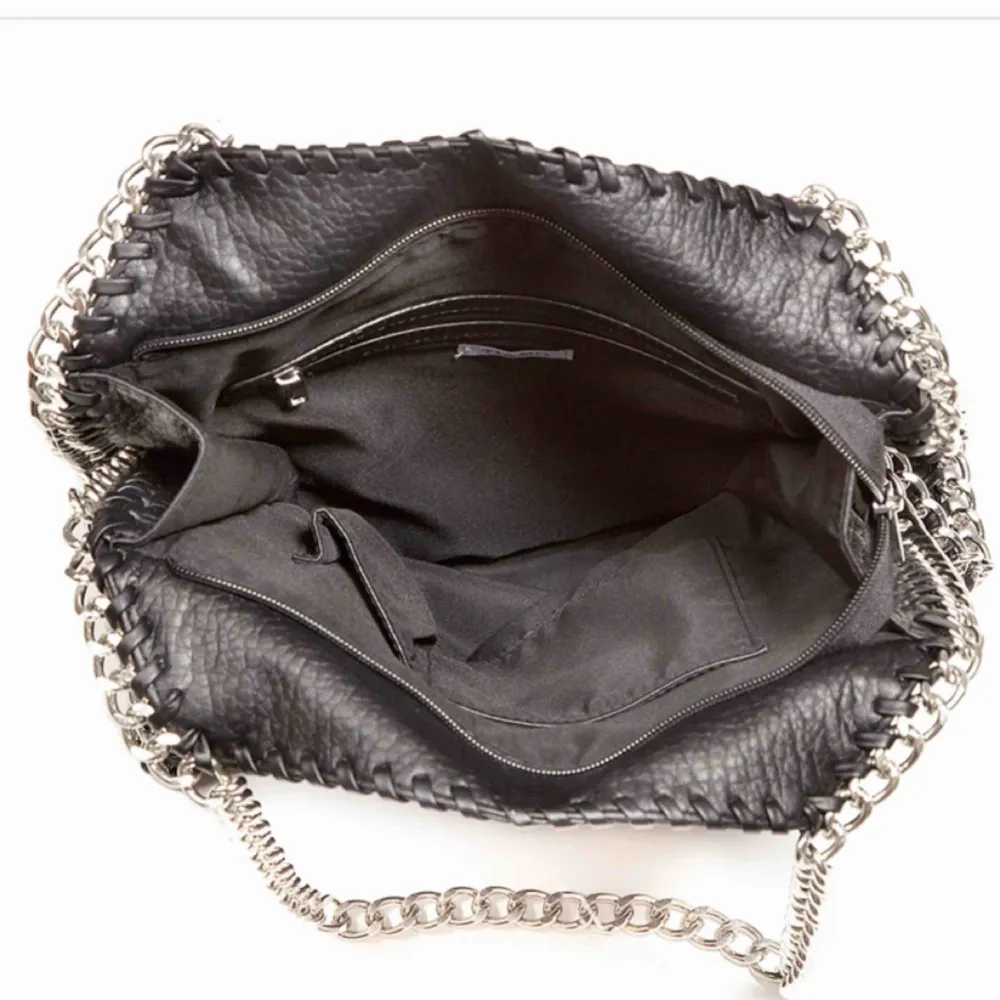 En svart väska från tiamo med silvriga kedjor. Väskan är väldigt fint sick. Köparen står för frakten . Väskor.