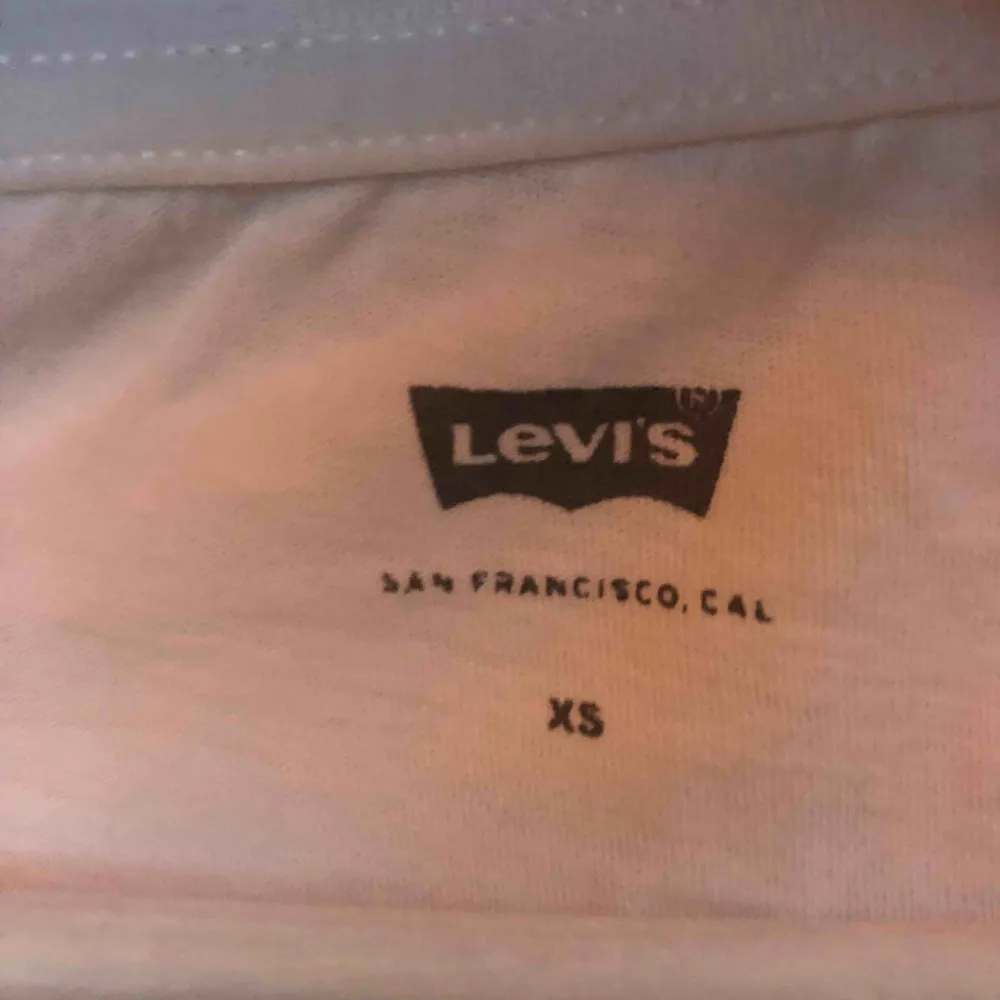 Säljer denna klassiska vita T-shirt med grå logga från Levi’s. Storlek XS.. T-shirts.