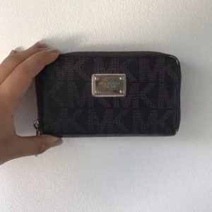  - Säljer min gamla Michael Kors plånbok. Superfin, men med en del synliga slitningar, bland annat på plattan och på kanterna, därav det låga priset. Frakt tillkommer med 30kr! Självklart äkta🎉👯