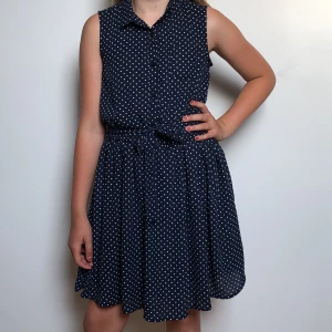 Blå prickig klänning med snöre  - På klänningen finns det även knappar vid bröstet. 