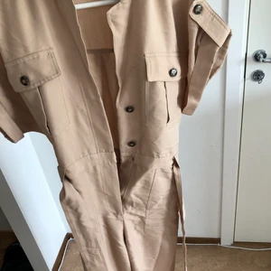 Jumpsuit - Beige jumpsuit från HM i storlek 36! Använd fåtal gånger. Har ett bälte i midjan och knappar samt blixtlås framtill 😍 100kr 