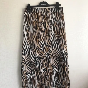 Kjol med djurmönster - Lång med djurmönster, har små knappar i mitten av kjolen som går hela vägen (från upp och ner) 