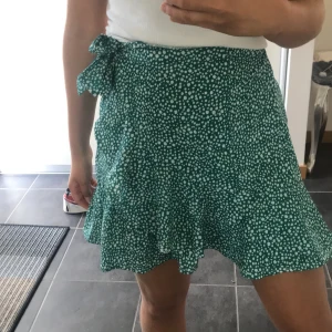 Grön volangkjol - En grön volangkjol med vita prickar i fint skick. Knytning upptill. Köpare står för frakt 🌸