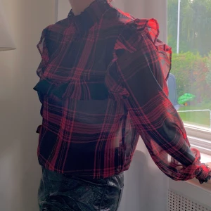 Rutig blus - Sjukt snygg blus med volangdetaljer! Röd och svartrutig. Från Gina! Ursäkta bilderna 😃. Använd en eller två gånger! Som ny. Storlek 40. Köpare står för frakt!
