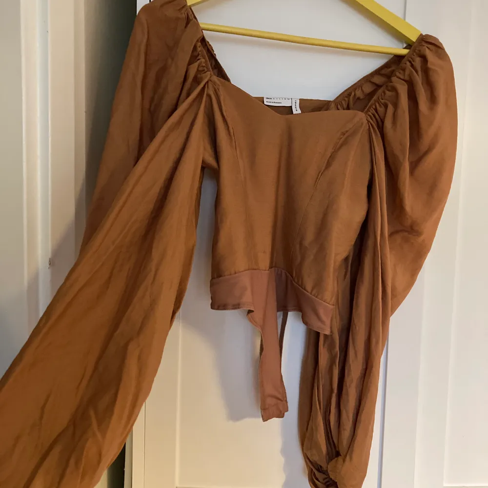 Brun body med struktur och vida ärmar från ASOS. Aldrig använd! Storlek 34.                                                 Material: Kontrast: 95 % polyester, 5 % elastan. Yttertyg: 83 % viskos, 17 polyamid. Nypris: 287kr.   Kan mötas upp på Kungsholmen. Vi postning står köparen för frakten:)  . Toppar.