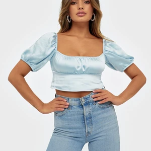 Superfin blå topp i satin storlek M - Säljer min sprillans nya topp som jag aldrig använt. Kort topp med puffärm som man kan dra ner och göra till off shoudler. Köpt på Nelly för 399kr. Passar även en S.