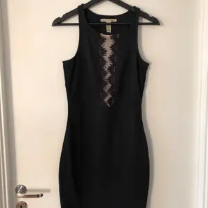 Svart klänning från Nellys märke NLY Trend, med beige mesh detalj över bröstet samt svart spetstyp. 