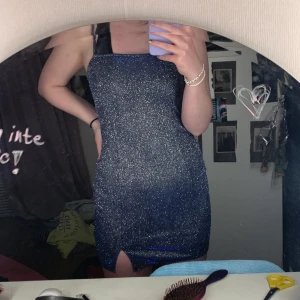 Glittrig klänning - En glittrig klänning med slits på högerbenet. Aldrig använd. Går nedanför rumpan. Inga märken eller skador, köparen står för frakten