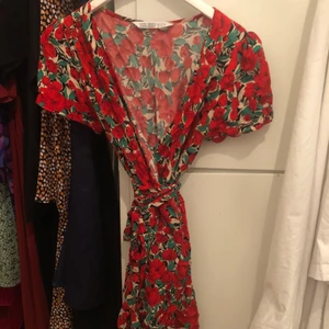 Söt rödblommig klänning  - Väldigt gullig blommig wrapklänning, stl M men passar mig som vanligtvis har XS/S. Ursäkta dålig bild, om du är intresserad kan jag skicka bilder när jag har den på mig! 