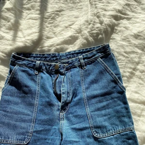 Blåa jeans - Blåa jeans med snygga detaljer. Korta i modellen. Ifrån Monki stl 27