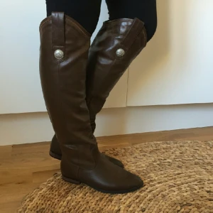  - Oanvända stövlar i fuskläder.
