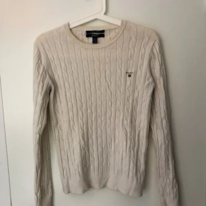  - Fin benvit/creme-färgad kabelstickad GANT-tröja. Fick små hål i tvättmaskin som är lagat så att det inte syns längre (se närbild nr 2). Använd ett fåtal gånger. 
